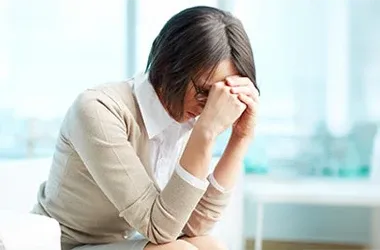 An individual is seated with their head resting on their hands, suggesting a moment of stress or contemplation.